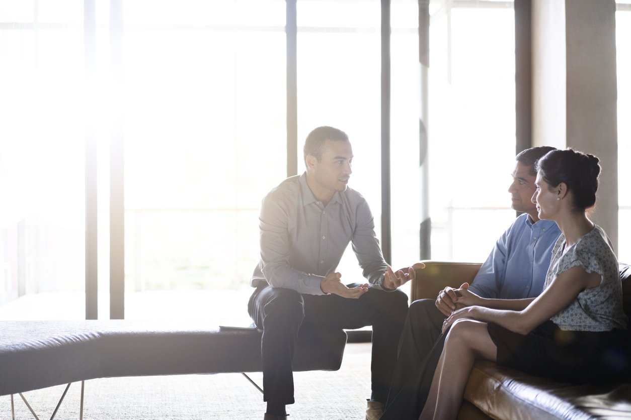 A man and woman sit relaxed in a bright room listening to a tax planning expert
