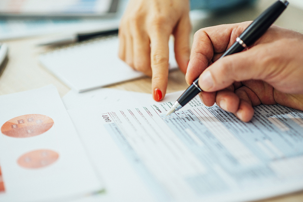 A person holding a pen is guided by a wills expert to fill in fields on a form